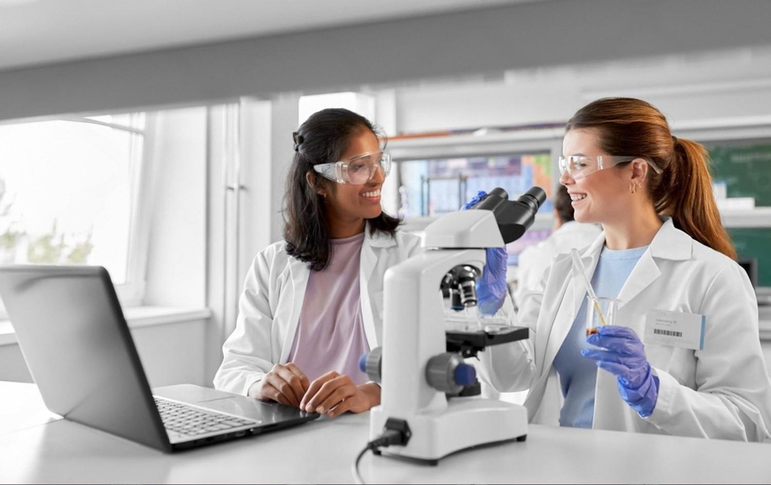 Two students in a school science lab working with a microscope, illustrating CBSE practical learning