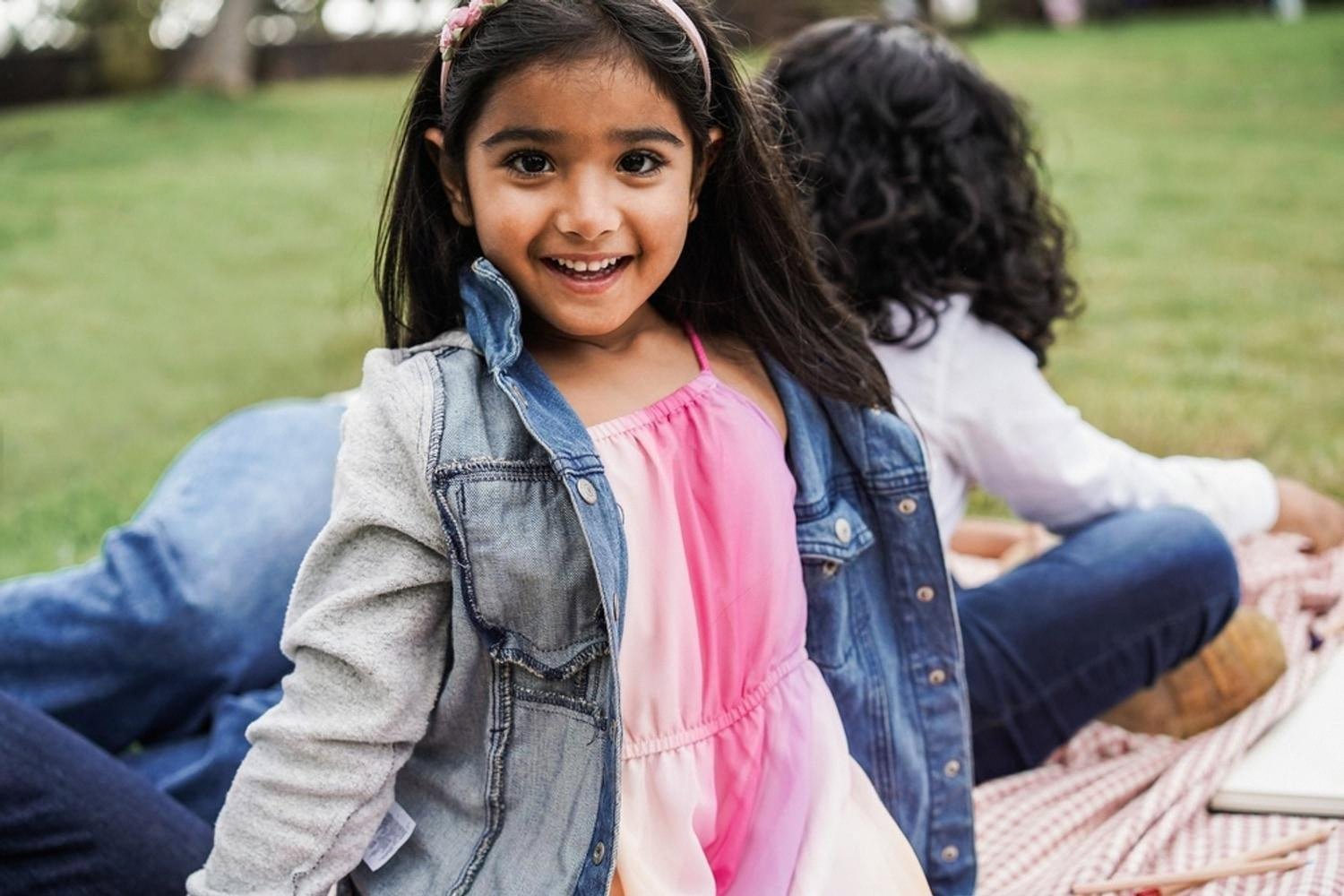 Smiling Indian girl sitting outdoors, representing children of expatriate families in the UAE